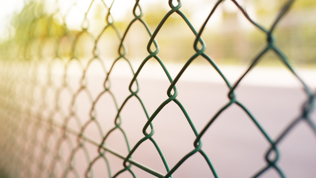 Wire fence with futsal field on background